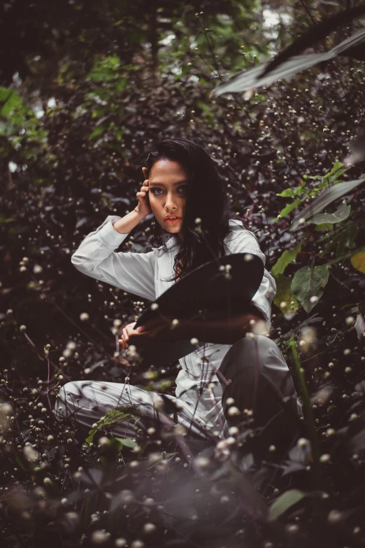 a woman sitting on the ground talking on a cell phone, an album cover, inspired by Elsa Bleda, pexels contest winner, lush foliage, standing in the rain, portrait of vanessa morgan, grey