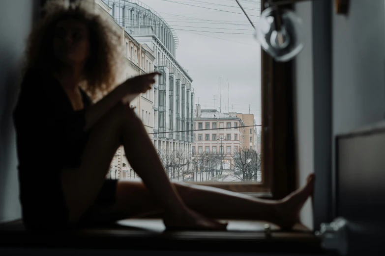 a woman sitting on a window sill looking out a window, inspired by Elsa Bleda, pexels contest winner, hyperrealism, helsinki, detailed legs looming over you, wavy hair spread out, in the middle of the city