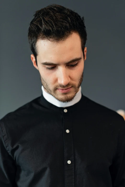 a man in a black shirt looking at his cell phone, an album cover, inspired by Modest Urgell, trending on unsplash, renaissance, wearing collar on neck, dressed like a cleric, a handsome man，black short hair, dress shirt