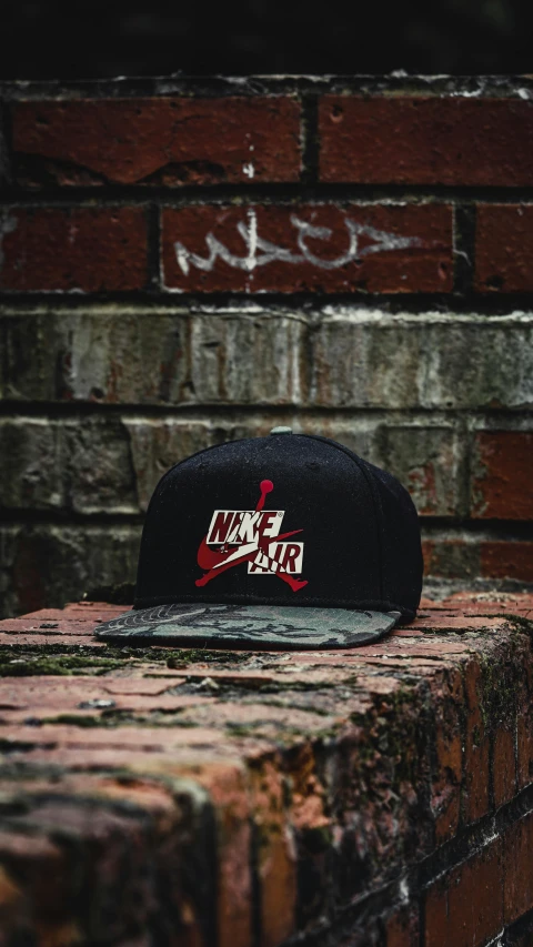 a baseball cap sitting on top of a brick wall, unsplash, graffiti, “air jordan 1, square, official screenshot, black and red