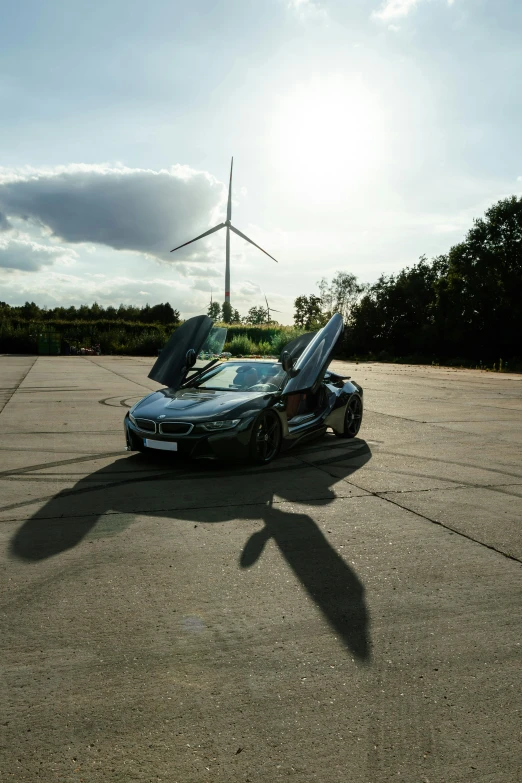 a car parked in a parking lot with a wind turbine in the background, by Paul Bird, happening, bmw i 8, low ultrawide shot, high quality photo, award winning. 4 k