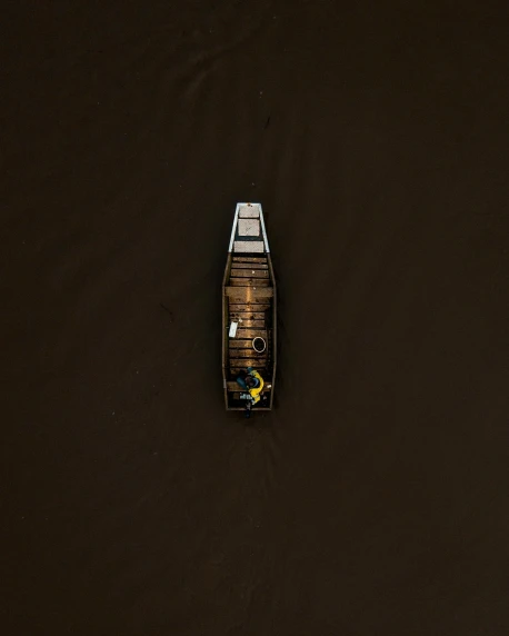 a small boat floating on top of a body of water, an album cover, by Jacob Toorenvliet, unsplash contest winner, black and brown colors, air shot, dark dingy, thumbnail