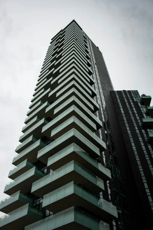 a tall building sitting in the middle of a city, inspired by Ricardo Bofill, unsplash, brutalism, toronto, low angle!!!!, overcast skies, tall terrace