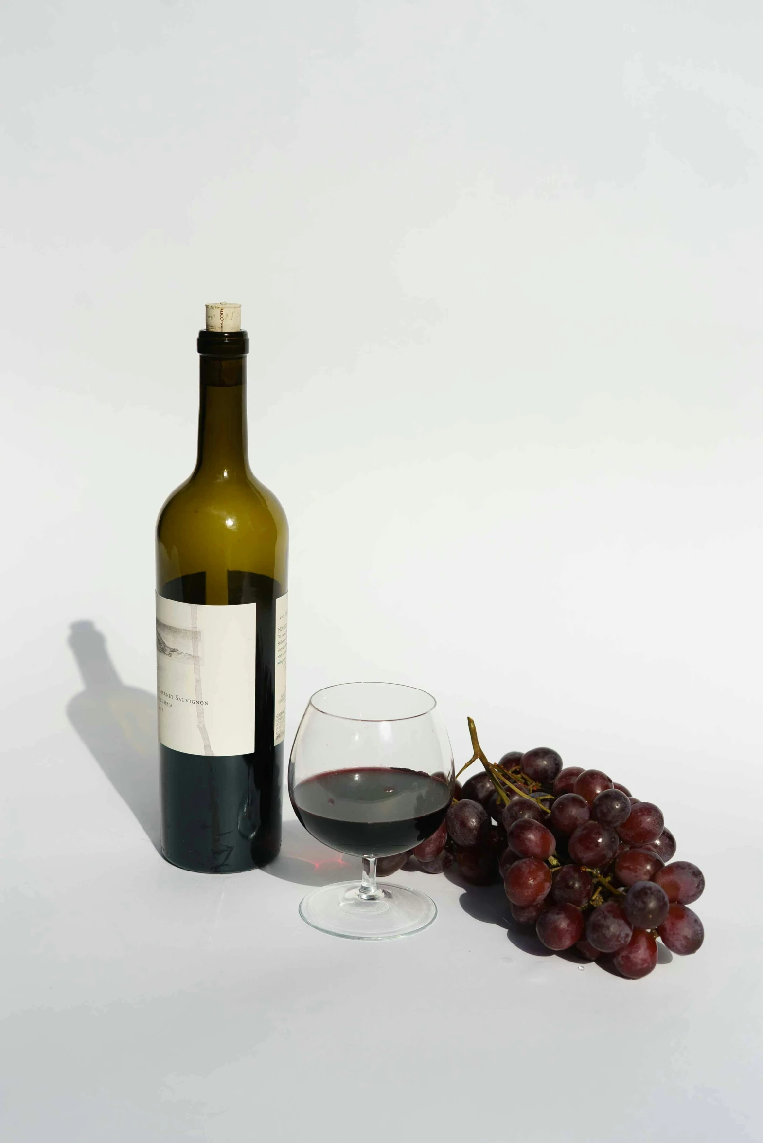 a bottle of wine sitting next to a glass of wine, translucent grapes, detailed product image, posed, portrait n - 9