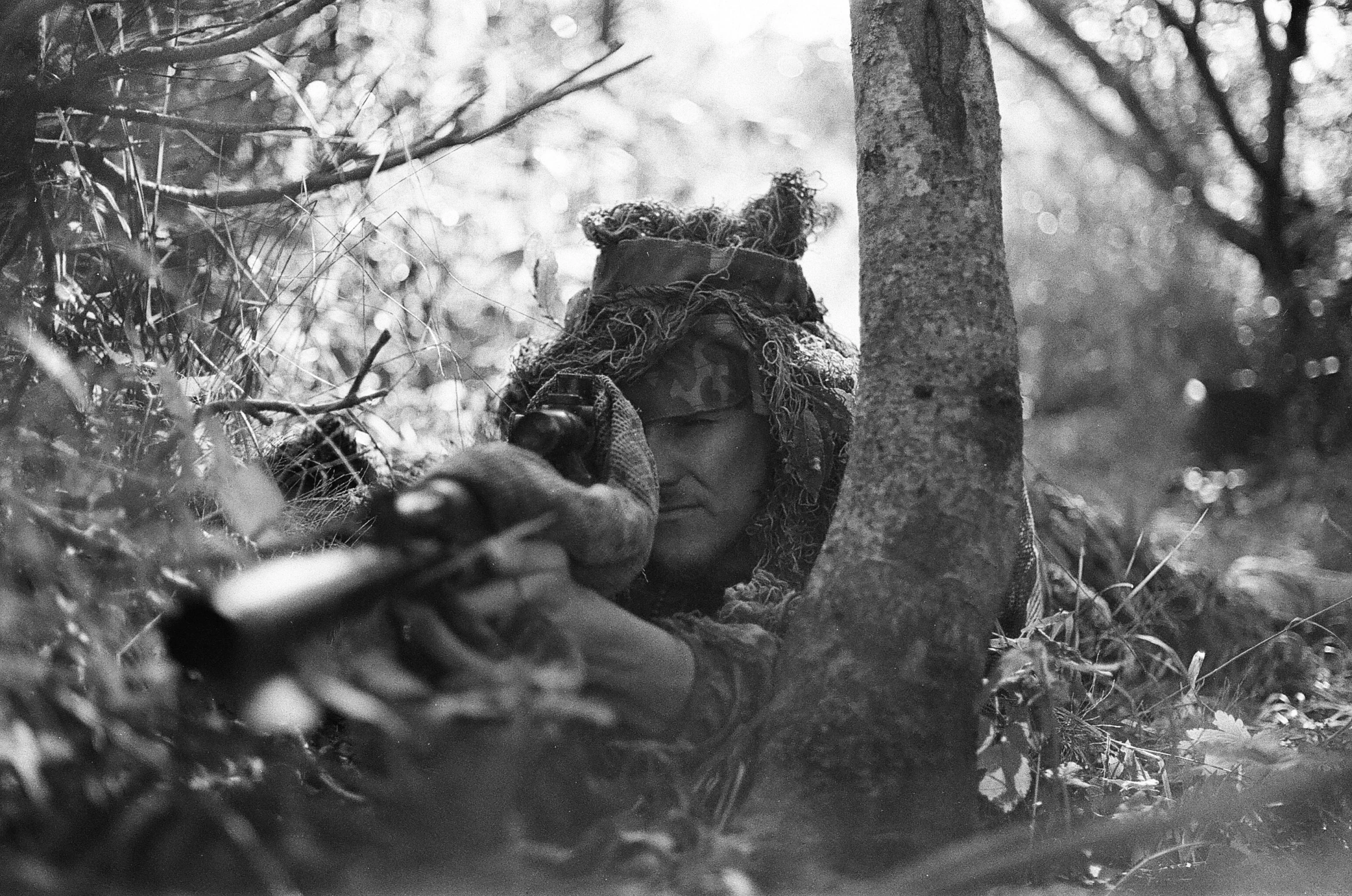 a black and white photo of a man with a gun, by John Hutton, camouflaged gear, 6 june 1944, beaver, a horned