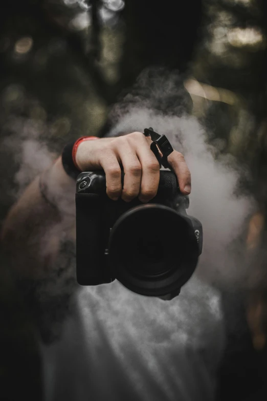 a person taking a picture with a camera, by Robbie Trevino, smoke fog dust, holding it out to the camera, dslr high resolution, rugged