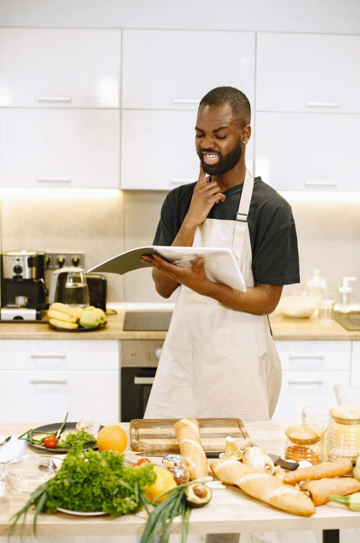 a man standing in a kitchen next to a table full of food, inspired by Richmond Barthé, pexels contest winner, holding a clipboard, black man, profile image, advanced technology