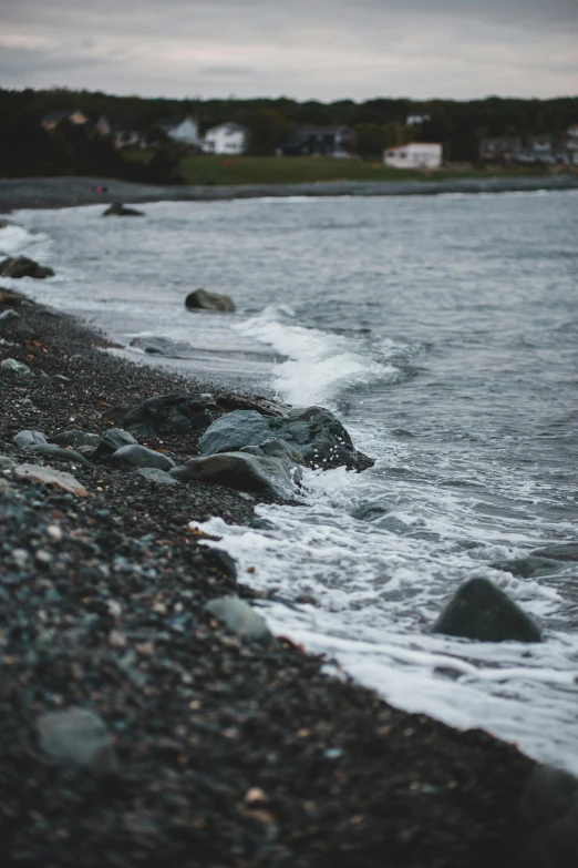 a rocky beach next to a body of water, a picture, inspired by Elsa Bleda, unsplash, wavy water, alaska, gravels around, low quality photo