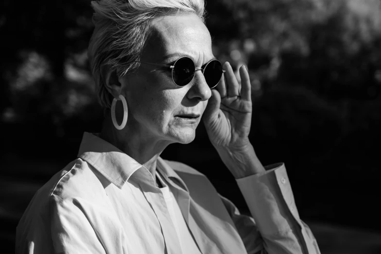 a black and white photo of a woman talking on a cell phone, by Emma Andijewska, pexels, bauhaus, jamie lee curtis, portrait tilda swinton, in sun glasses, white haired lady