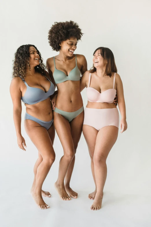 three women in bikinis standing next to each other, sizes and colors, soft muted colors, wearing bra, full product shot