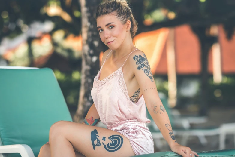 a woman sitting on a beach chair with a tattoo on her arm, a tattoo, pexels contest winner, cute girl wearing tank suit, mid 2 0's female, student, various posed