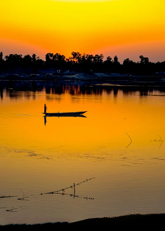 a person in a boat on a lake at sunset, inspired by Steve McCurry, pexels contest winner, hurufiyya, cambodia, on a reflective gold plate, today\'s featured photograph 4k, scenic view of river