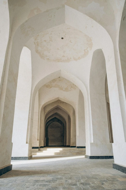 the inside of a building with columns and arches, inspired by Alberto Morrocco, unsplash, oman, white walls, tall entry, rounded roof