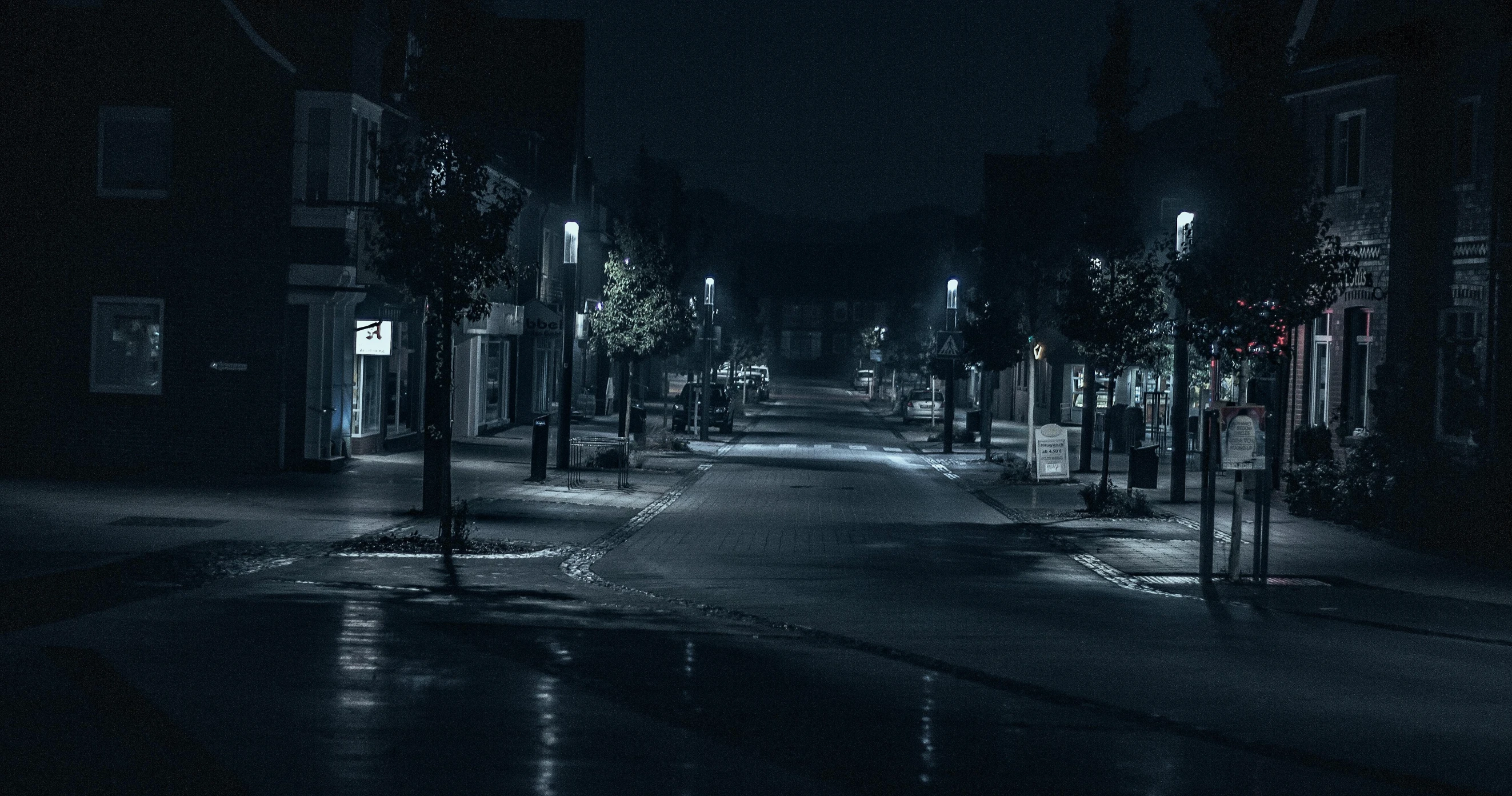 a black and white photo of a street at night, inspired by Gregory Crewdson, pexels contest winner, hyperrealism, midwest town, horror setting, street of teal stone, videogame still