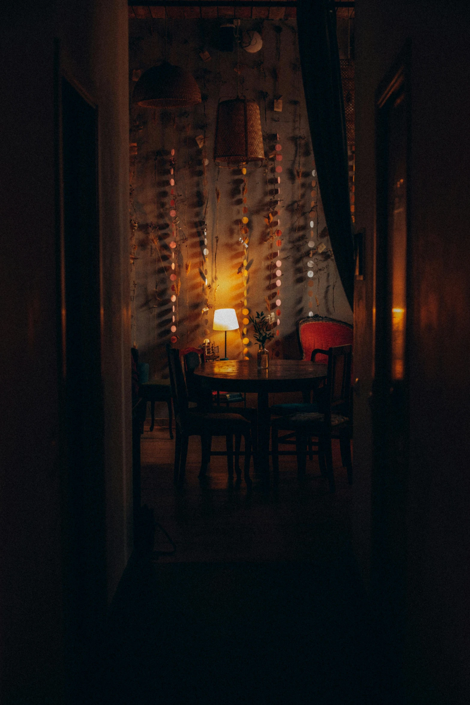 a dimly lit room with a table and chairs, unsplash, tea drinking and paper lanterns, back room, looking out, low iso