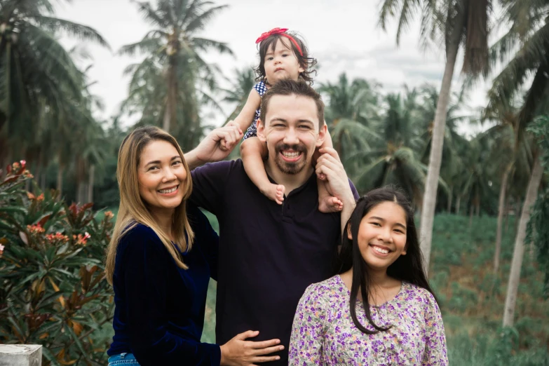 a family poses for a picture in front of palm trees, a portrait, inspired by Ruth Jên, pexels contest winner, in front of a forest background, avatar image, asian female, holiday