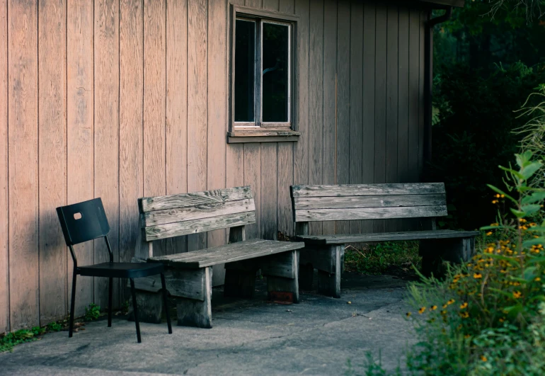 a couple of wooden benches sitting next to a building, unsplash, crewdson, cottage, brown, waiting room