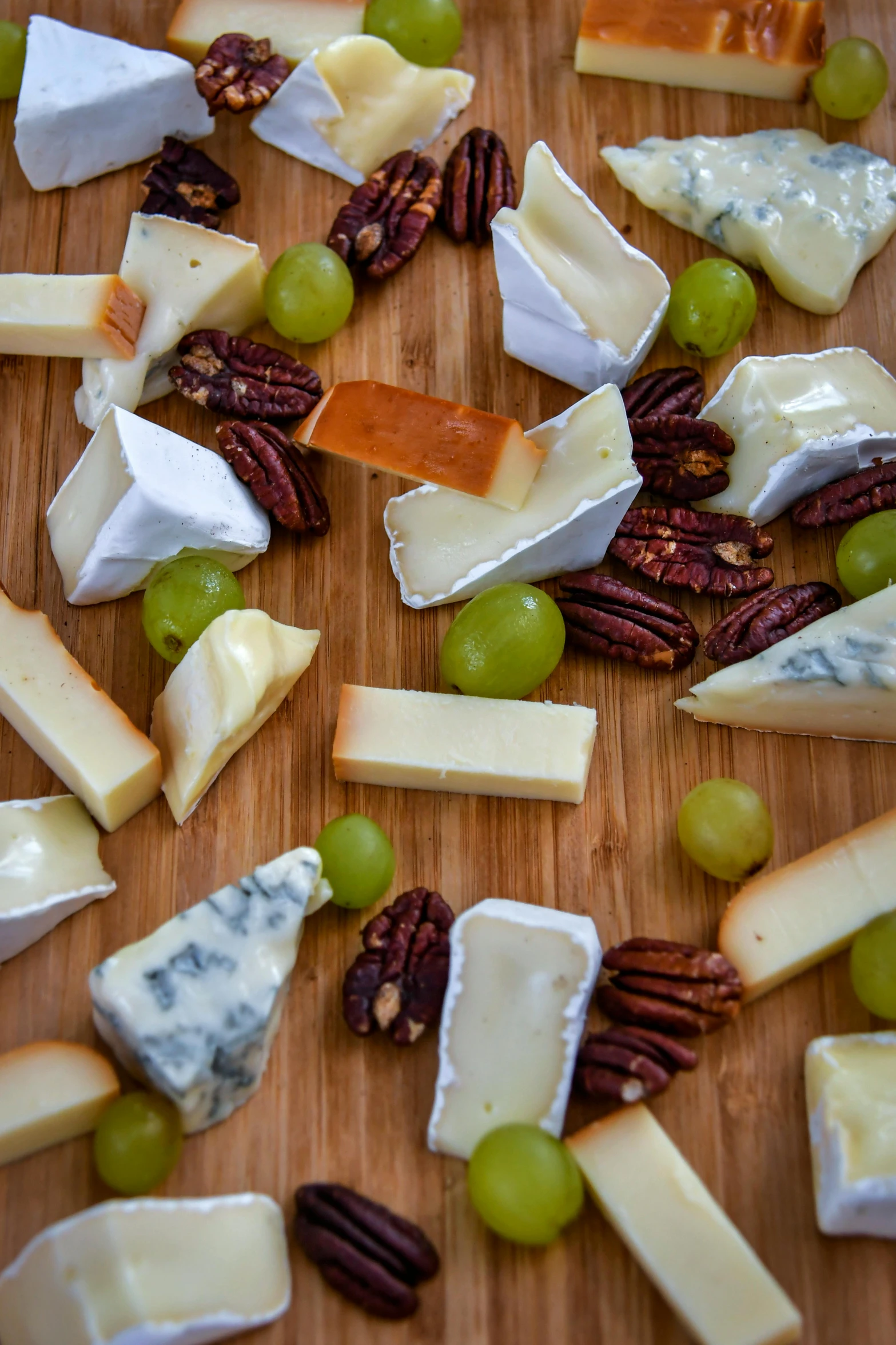 a wooden cutting board topped with lots of cheese and grapes, thumbnail, puttin, nut, chilean