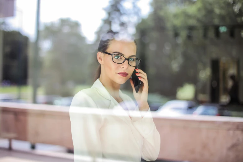 a woman in glasses talking on a cell phone, by Matthias Weischer, pexels contest winner, realism, elegant high quality, window, caucasian, people at work