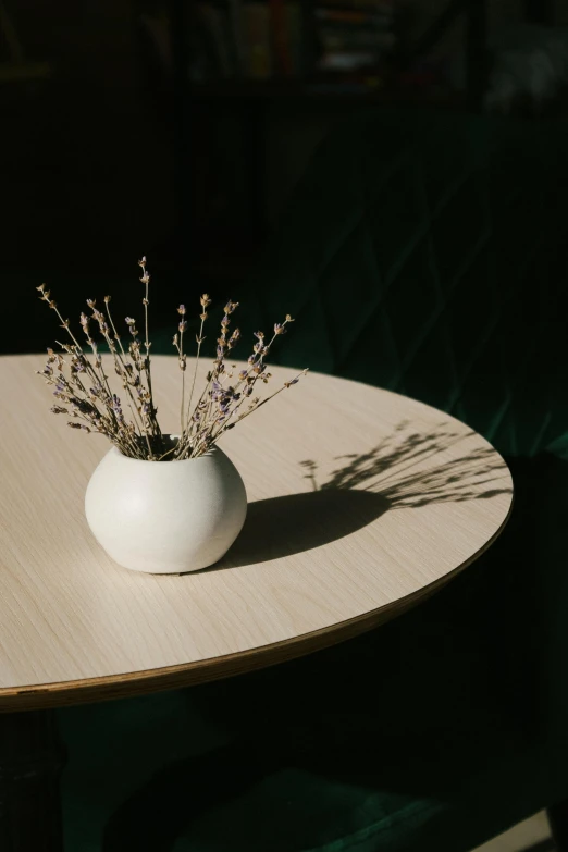 a white vase sitting on top of a wooden table, inspired by Constantin Hansen, trending on unsplash, cafe tables, small crown, wilted flowers, round form