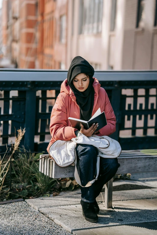 a woman sitting on a bench reading a book, inspired by Maryam Hashemi, wearing a hoodie, holding notebook, wearing a turtleneck and jacket, gen z