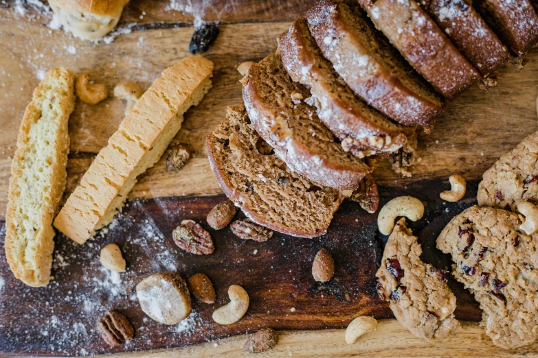 a wooden cutting board topped with lots of cookies, by Daniel Lieske, pexels, renaissance, brown bread with sliced salo, 🦩🪐🐞👩🏻🦳, nut, half turned around