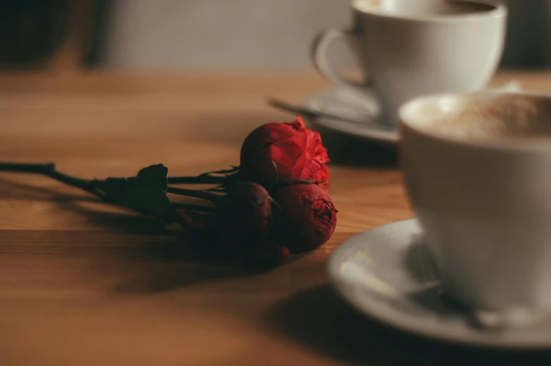 two cups of coffee sitting on top of a wooden table, pexels contest winner, romanticism, red roses, candid photograph, from the side, subtle details