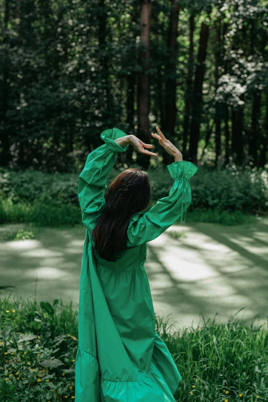 a woman in a green dress is throwing a frisbee, inspired by Li Di, unsplash, forest ritual, back, green robe, t pose