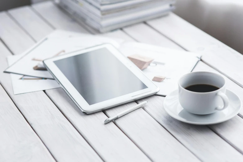 a tablet computer sitting on top of a table next to a cup of coffee, a picture, private press, 9 9 designs, white finish, curated collections, zoomed in