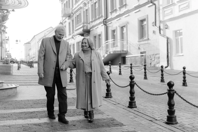 a man and a woman walking down a street, a black and white photo, by Maksimilijan Vanka, pexels, middle age, happy couple, anna kovalevskaya, two old people