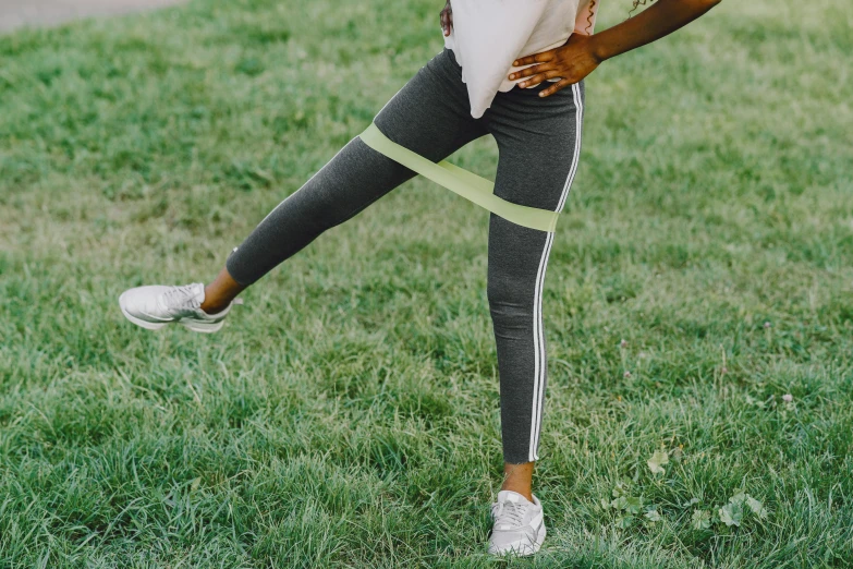 a woman standing on top of a lush green field, a colorized photo, trending on pexels, happening, wearing fitness gear, knobbly knees, white limbo, grey