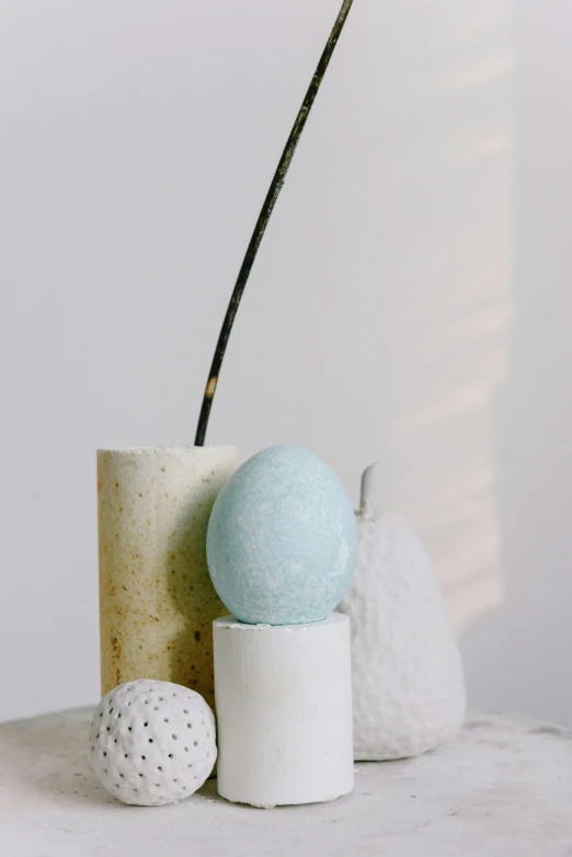 a white vase sitting on top of a table, an abstract sculpture, inspired by Emil Carlsen, trending on unsplash, holding easter eggs, soft blue texture, on a candle holder, detailed product image