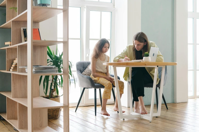 a woman and a little girl sitting at a table, pexels contest winner, minimalist home office, sitting on designer chair, carefully designed, a wooden