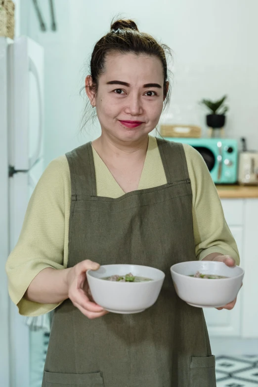 a woman holding two bowls of food in her hands, inspired by Tan Ting-pho, dau-al-set, portrait image, tv show still, recipe, professional profile photo