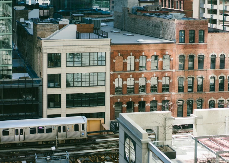 a train traveling through a city next to tall buildings, inspired by Thomas Struth, pexels contest winner, renaissance, brick building, ignant, midwest town, wide high angle view