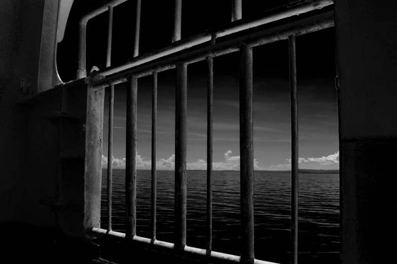 a black and white photo of a window with a view of the ocean, pexels, cages, criminal, cg original, mane
