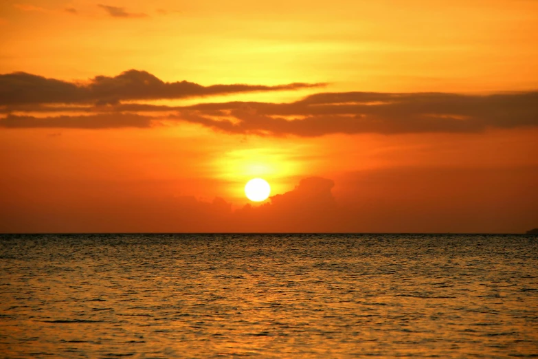 the sun is setting on the horizon of the ocean, by Robbie Trevino, pexels contest winner, romanticism, bright yellow and red sun, jamaica, brown, no cropping