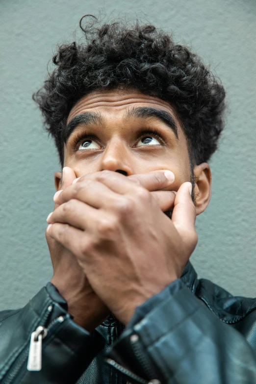 a man in a leather jacket covers his mouth with his hands, trending on pexels, imaan hammam, terrified, gray men, square masculine jaw