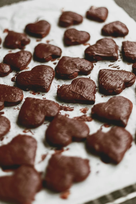 a tray of chocolate hearts sitting on top of a table, by Jessie Algie, pexels, lots of wrinkles, brunettes, made of glazed, thumbnail