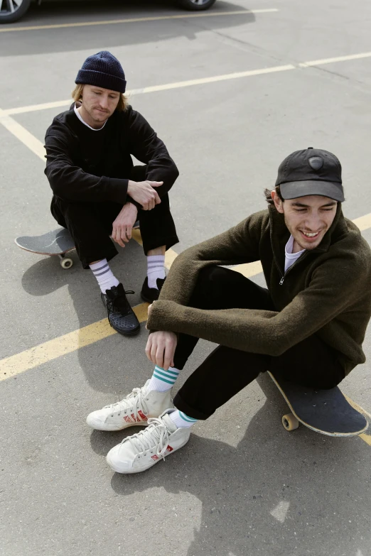 two young men sitting on skateboards in a parking lot, inspired by Seb McKinnon, sock cap, federation clothing, corduroy, promotional image