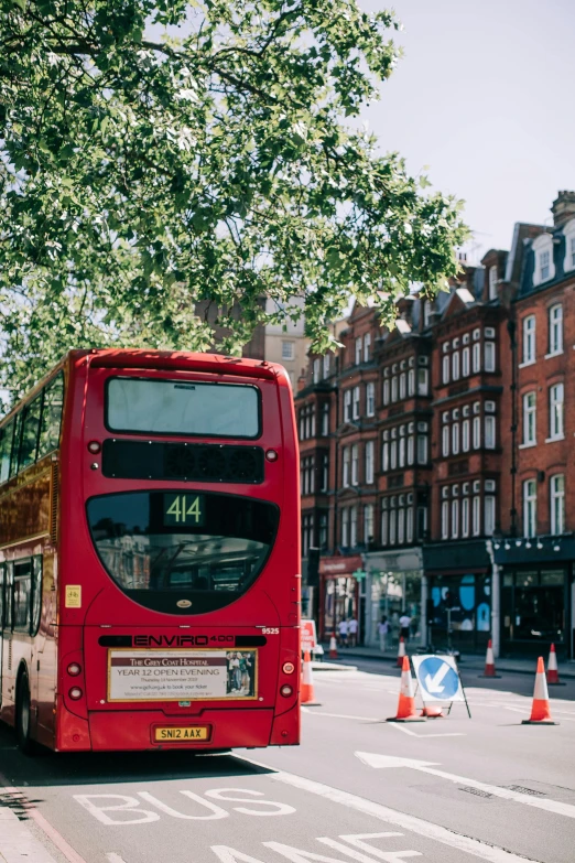 a red double decker bus driving down a street, by Nina Hamnett, trending on unsplash, art nouveau, square, esher, summer day, standing on street corner