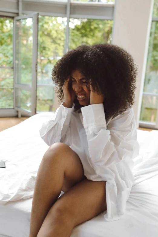 a woman sitting on a bed talking on a cell phone, messy curly hair, in pain, 2019 trending photo, 6 : 3 0 am