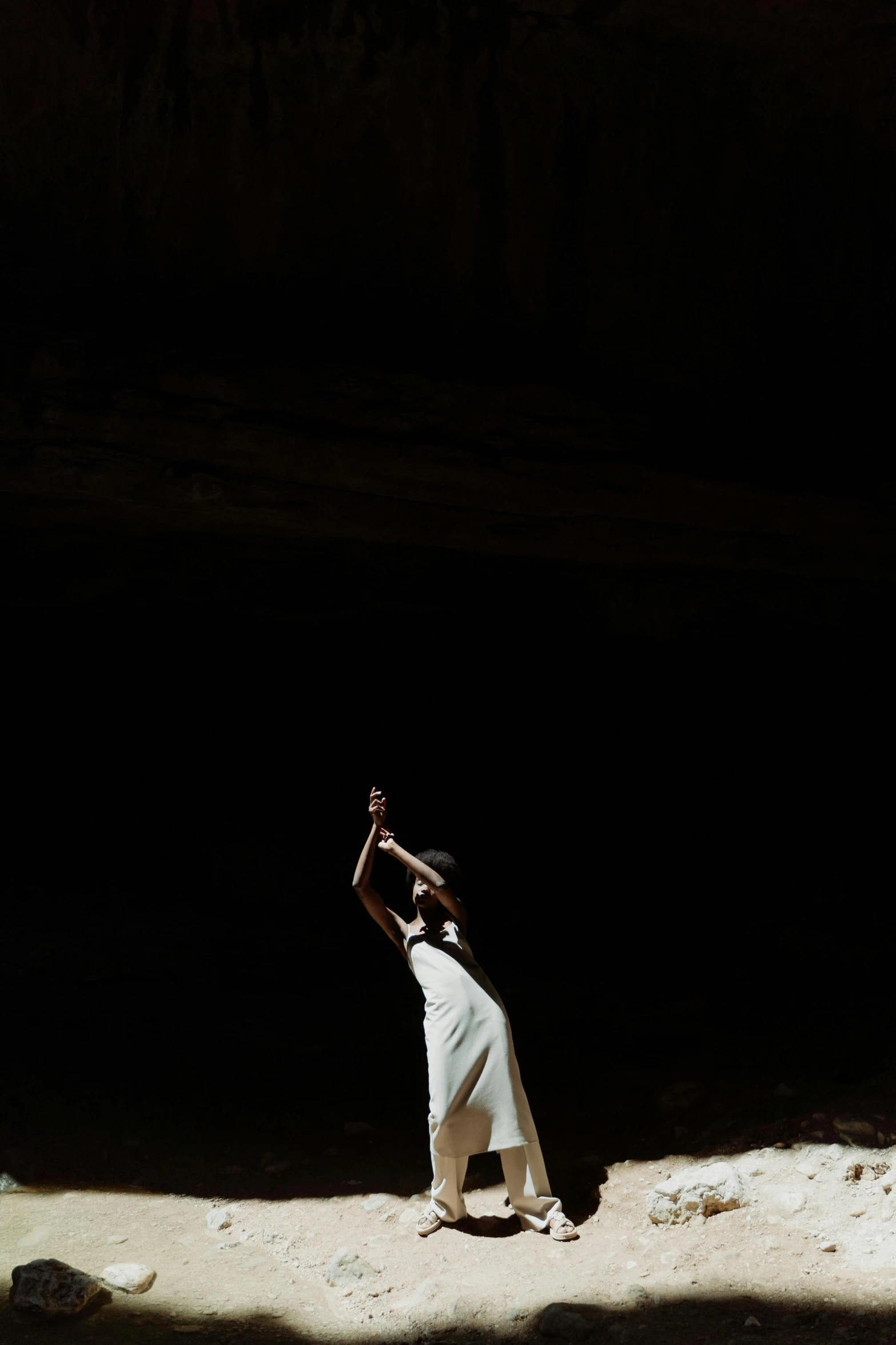 a man that is standing in the dirt, by irakli nadar, art photography, girl in white dress dancing, in a cave. underexposed, shot on hasselblad, 15081959 21121991 01012000 4k