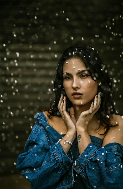 a woman standing in the rain with her hands on her face, an album cover, inspired by Elsa Bleda, trending on pexels, hyperrealism, snowflakes falling, brunette woman, studio shoot, looking serious