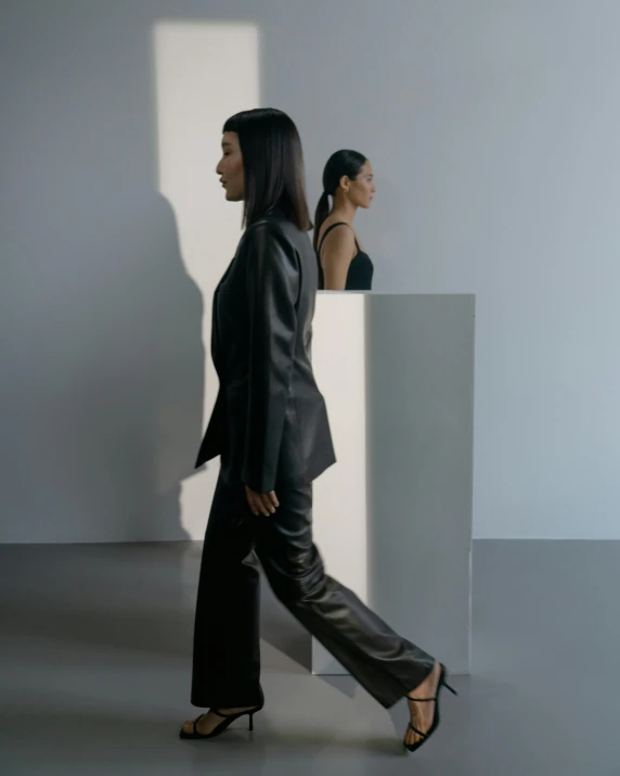 two women standing next to each other in a room, inspired by Vanessa Beecroft, trending on unsplash, holographic suit, side profile view, an asian woman, wearing causal black suits