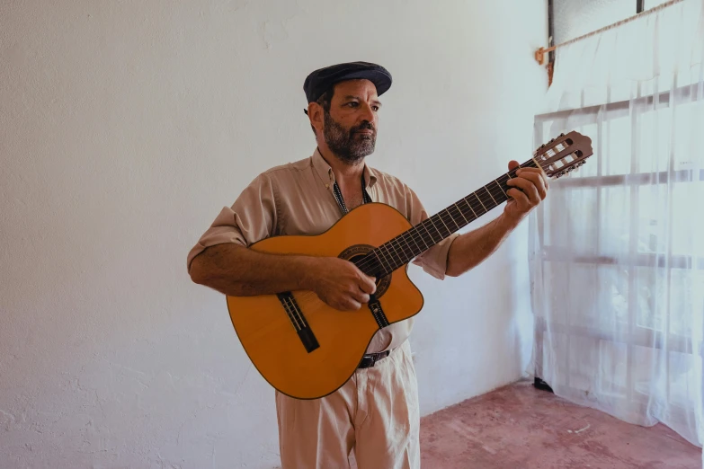 a man holding a guitar in a room, inspired by Agustín Fernández, pexels contest winner, figuration libre, traditional corsican, standing upright, profile image, wearing a straw hat and overalls