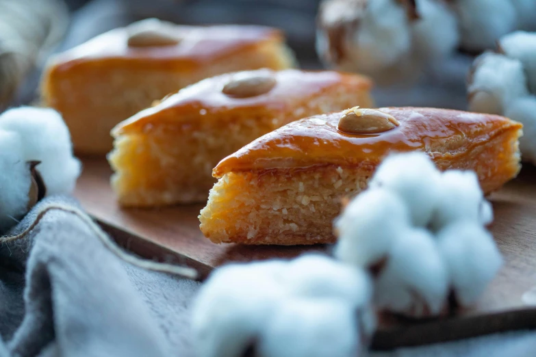 a couple of pastries sitting on top of a wooden cutting board, hurufiyya, up-close, fanoos, glazed, cosy