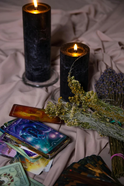 a couple of candles sitting on top of a bed, a still life, trending on pexels, renaissance, high detailed + tarot card, black and purple, books and flowers, full body in shot