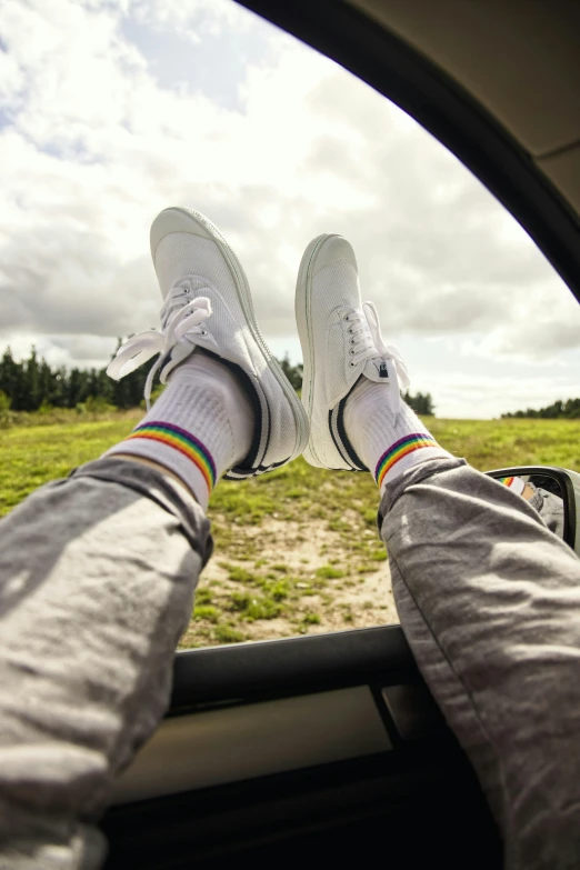 a person sitting in the passenger seat of a car, inspired by Okuda Gensō, trending on unsplash, renaissance, white shoes, countryside, striped socks, view from below