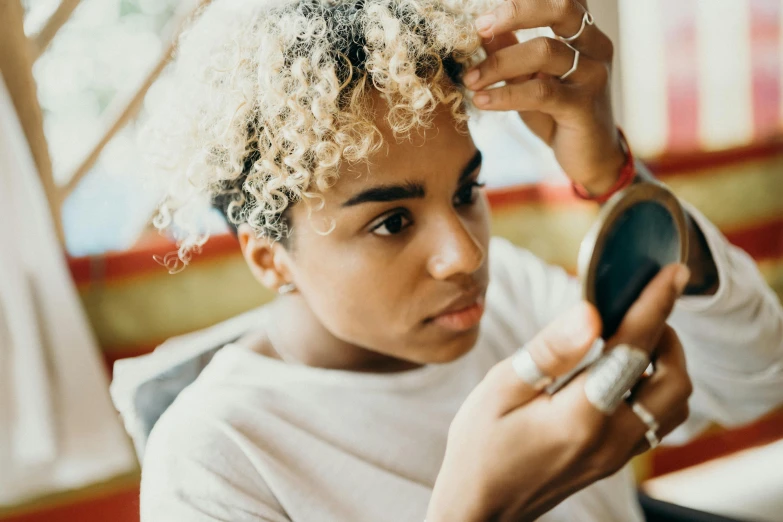 a woman with curly hair combing another woman's hair, by Joe Bowler, trending on pexels, afrofuturism, relaxed eyebrows, bleached blonde short hair, looking in mirror, thumbnail